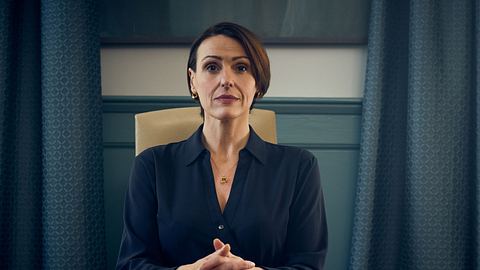 Die Schauspielerin Suranne Jones sitzt an einem Schreibtisch und schaut in die Kamera. - Foto: Des Willie/Netflix © 2025