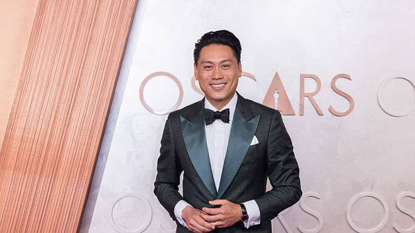 Jon M. Chu ist vor einer Fotowand der Oscars. Er trägt einen schwarzen Anzug mit einer schwarzen Fliege.  - Foto:  IMAGO / Cinema Publishers Collection