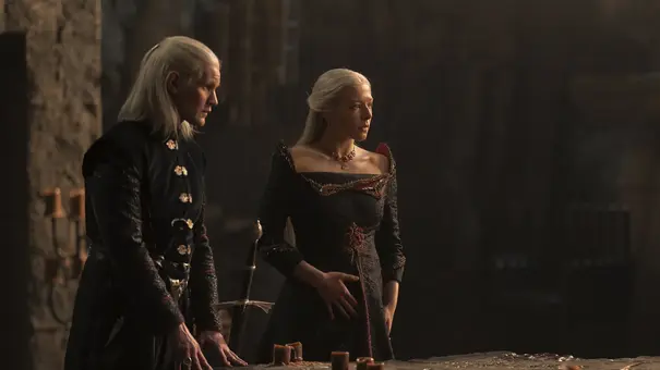 Rhaenyra und Daemon stehen nebeneinander am Ende eines Tisches und schauen jemand entgeistert an. - Foto: Ollie Upton/HBO Rhaenyra und Daemon stehen nebeneinander am Ende eines Tisches und schauen jemand entgeistert an. - Foto: Ollie Upton/HBO