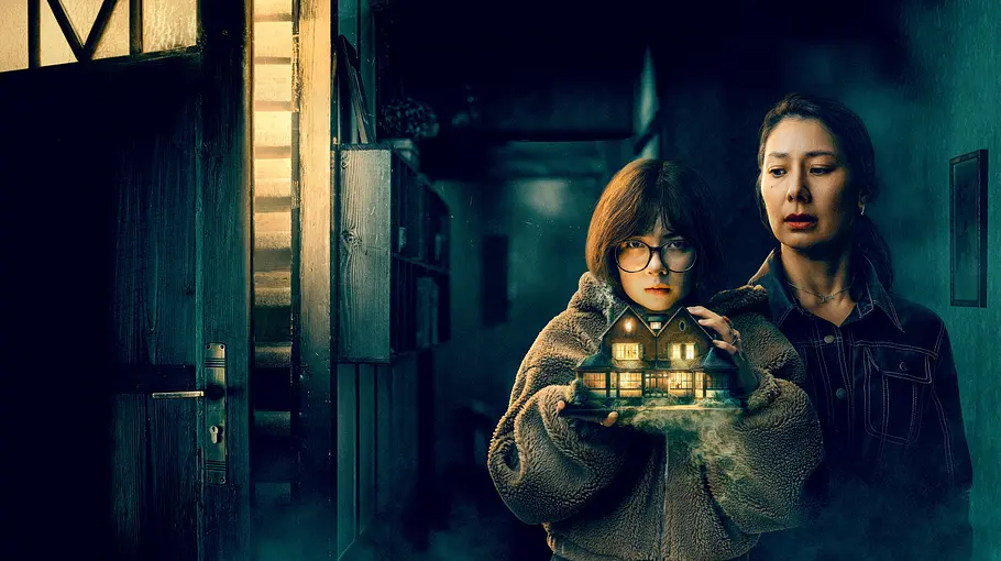 House of Yang: Eine junge Person mit Brille hält ein beleuchtetes Modellhaus. Hinter ihr steht eine Frau in einem dunklen Flur neben einer offenen Tür.