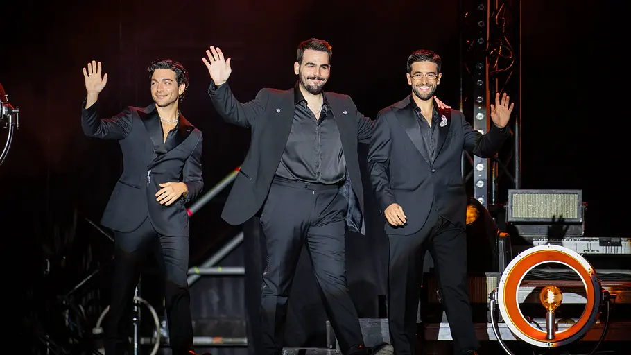 Il Volo ZDF Weihnachtsshow Die drei Mitglieder von Il Volo stehen in dunklen Anzügen auf einer Bühne und winken lächelnd.