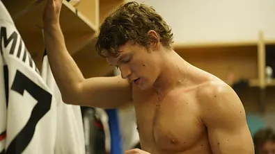 Ilya steht in der Umkleidekabine und schaut auf sein Handy. - Foto: Sabrina Lantos/HBO Max