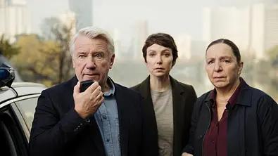 Im Schatten der Angst - Der Skorpion: Neben einem Auto steht der forensische Psychiater Paul Kressmann (Jörg Schüttauf) und hält ein Funkgerät in der Hand. Neben ihm stehen Karla Eckhardt (Julia Koschitz) und Kommissarin Radek (Susi Stach). Alle drei wirken äußerst angespannt und blicken in die gleiche Richtung. - Foto: ZDF / Victoria Herbig