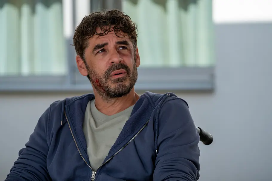 Einfach Elli Einfach Elli - Verzeihen: Der schwer verletzte Toni Eisler (Tobias Oertel) sitzt in einem Rollstuhl. In seinem Gesicht sind diverse Verletzungen sichtbar.