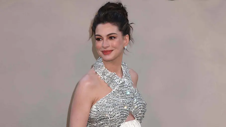 Anne Hathaway auf der Premiere Anne Hathaway steht auf dem roten Teppich der Premiere von The Odyssey in einem fließenden, bodenlangen Kleid mit glitzerndem Oberteil und hellem, weich fallendem Rock. Sie lächelt leicht und trägt die Haare zu einem hohen Dutt.