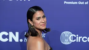 Steffi Brungs posiert mit dunklem, schulterlangem Haar und schulterfreiem Kleid vor einer blauen Wand mit weißen Logos. - Foto: IMAGO / Sven Simon
