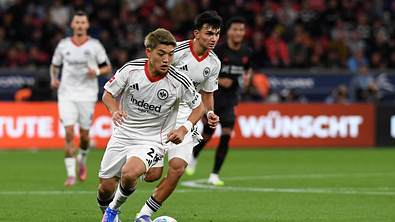 Ritsu Doan dribbelt beim Spiel von Eintracht Frankfurt. Im Hintergrund ist Can Uzun zu sehen! - Foto: IMAGO / DeFodi Images