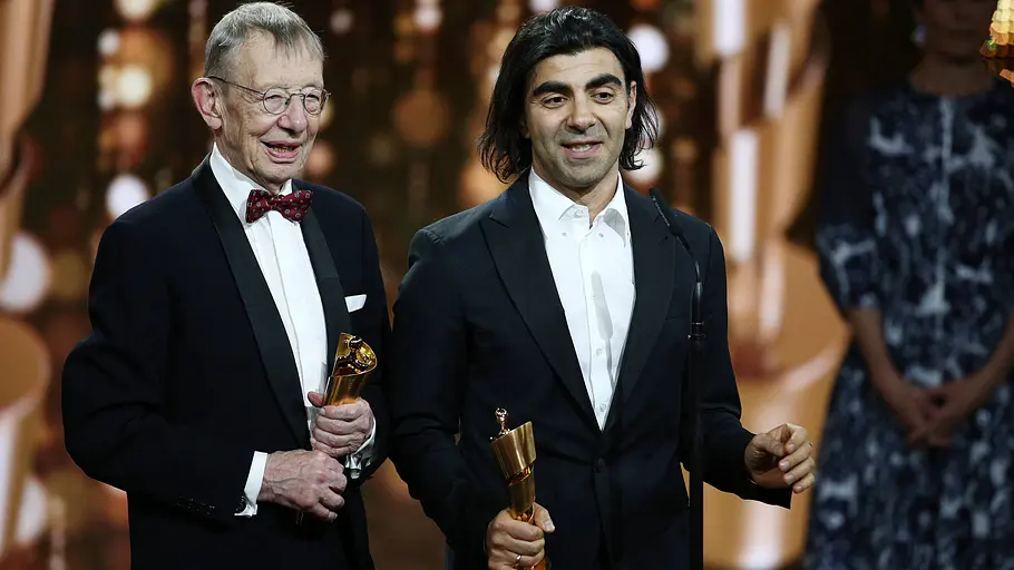 Hark Bohm und Fatih Akin stehen gemeinsam auf einer Bühne und halten Filmpreise in den Händen.