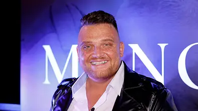 Menowin Fröhlich lächelt in die Kamera. Er trägt ein weißes Hemd und eine schwarze Lederjacke. - Foto: IMAGO / Panama Pictures