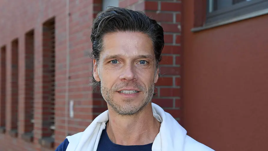 Stephen Dürr steht vor einem Haus und schau in die Kamera