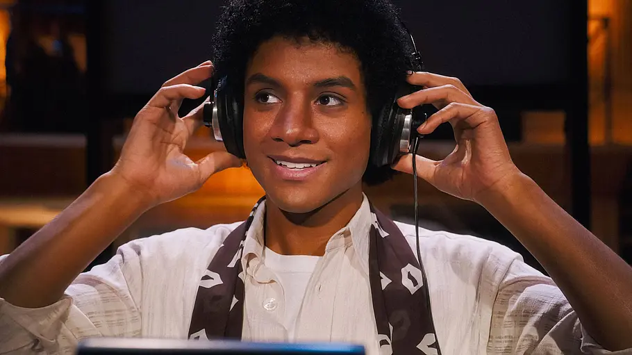 Jaafar Jackson als Michael Jackson Jaafar Jackson steht als Michael Jackson im Musikstudio. Er hat Kopfhörer auf den Ohren, die er mit den Händen greift. Er lächelt.
