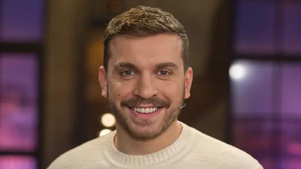 Edin Hasanovic in hellem Pullover lächelt in die Kamera - Foto:  IMAGO / Sven Simon