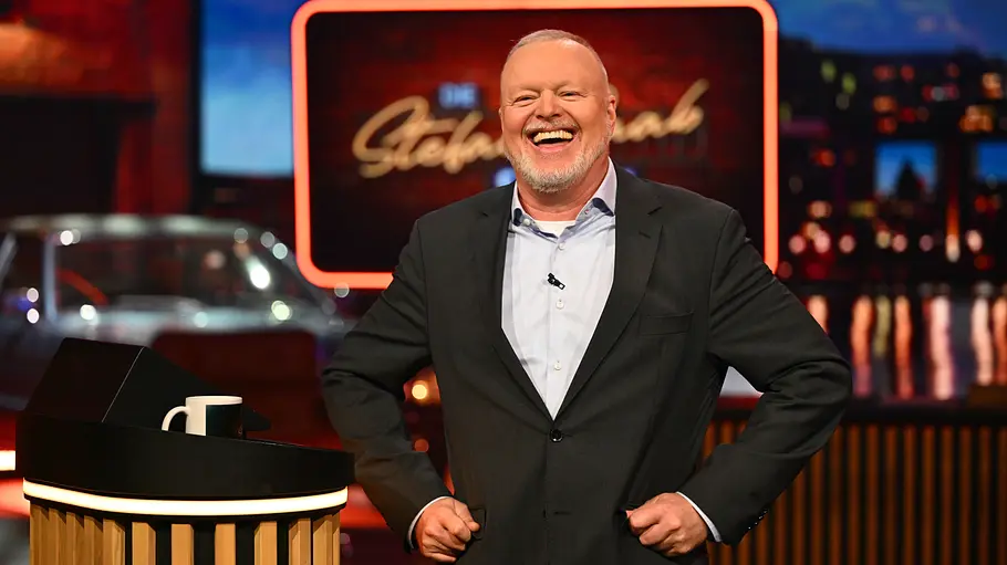 Immerhin Stefan Raab scheint noch Spaß zu haben. Stefan Raab steht lachend im dunklen Anzug mit den Händen an den Hüften neben einem Pult im bunt beleuchteten Studio.