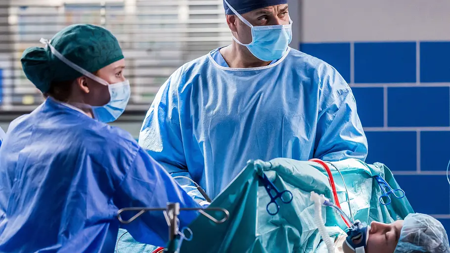 Dr. Matteo Moreau (Mike Adler, r.) und Tamar Hummel (Linda Kummer, l.) operieren El Fabecks (Antonia Baumgartner, liegend) Rippenserienfraktur, als deren Blutdruck wieder verrückt spielt.