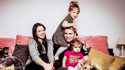 Anne Wünsche sitzt auf dem Sofa, neben ihr ihre Töchter Miley und Juna und ihr Ex-Freund Henning. - Foto: RTL II