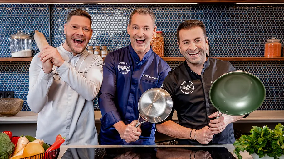In der Jubiläumswoche fällt die „Mein Lokal, Dein Lokal“-Programmplanung aus der Reihe. Robin Pietsch, Christian Henze und Ali Güngörmüs lachen in Kochjacken und halten einen Holzlöffel, einen Topf und eine Pfanne.