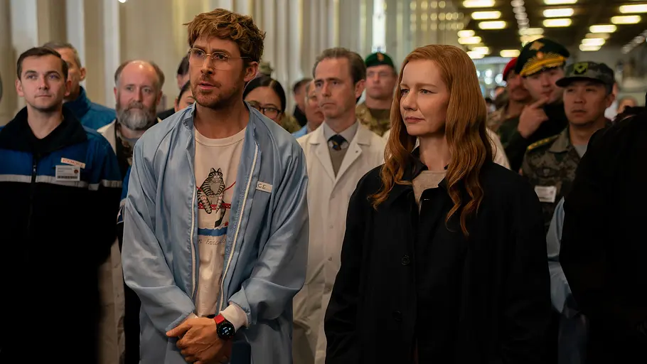 In ihrer Karaoke-Szene weckt Sandra Hüller „Toni Erdmann“-Erinnerungen. Ryan Gosling und Sandra Hüller stehen vor mehreren Männern.
