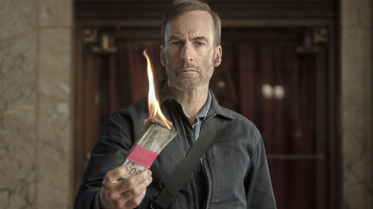 Bob Odenkirk hält im Film „Nobody“ ein brennendes Bündel Dollarscheine.