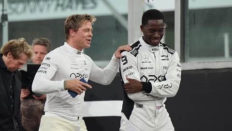Brad Pitt und Damson Idris stehen in weißer Rennfahrermontur auf einer Rennstrecke.  - Foto: IMAGO / Eibner
