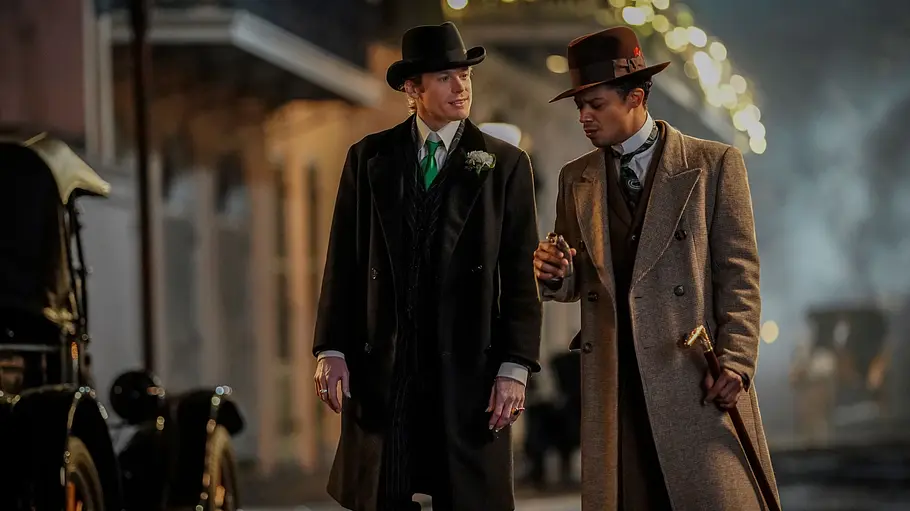 Interview with the Vampire Lestat de Lioncourt und Louis de Pointe du Lac gehen in eleganter Kleidung und mit Hüten durch eine nächtliche Straße in New Orleans – eine Szene aus der Vampirserie „Interview with the Vampire“.