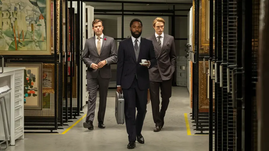 Jack Cutmore-Scott (links), John David Washington (Mitte) und Robert Pattinson (rechts) betreten ein Kunstlager.