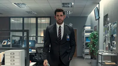 John Krasinksi geht als Jack Ryan in einem Anzug durch ein Büro. - Foto: Attila Szvacsek/Prime Video