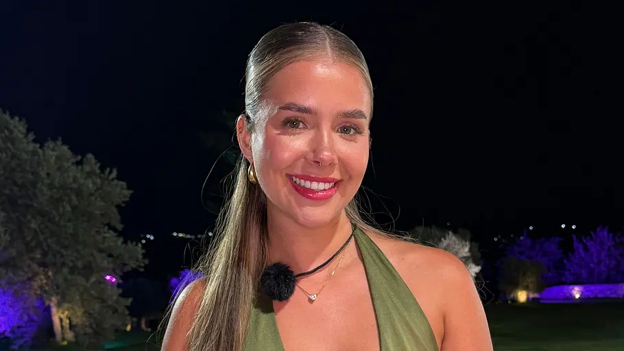 Jana, 26 Eine lächelnde Frau im olivgrünen Kleid mit schwarzem Gürtel steht nachts vor einem Pool mit Schwimmringen.
