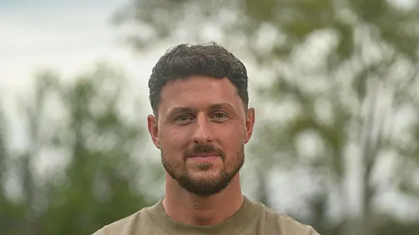 Jannik Kontalis in einem grünen T-Shirt, verschränkt die Arme und lächelt in die Kamera - Foto: RTL