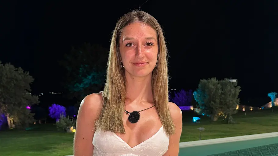 Jasmin, 22 Eine Frau im weißen Kleid steht nachts an einem Pool. Im Hintergrund sind Bäume und Rasenflächen farbig beleuchtet.