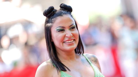 Jasmin Herren trägt zwei Space-Buns und grünen Lidschatten. Sie wird breit lächelnd von der Seite abgelichtet. - Foto: IMAGO / Panama Pictures