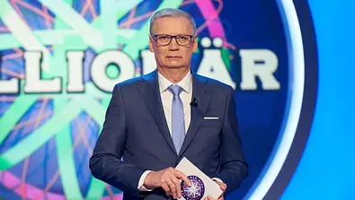Günther Jauch steht vor dem Logo von Wer wird Millionär? - Foto: RTL / Guido Engels