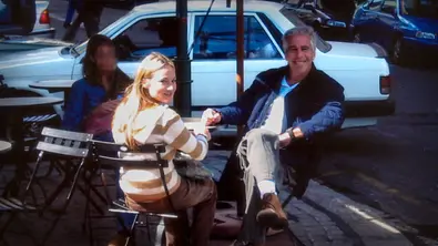 Die junge Frau Chauntae Davies und Jeffrey Epstein sitzen in Folge 3 von Stinkreich an einem Tisch und schauen in die Kamera. - Foto: Netflix