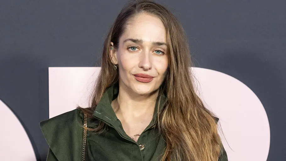 Jemima Kirke Jemima Kirke trägt einen dunkelgrünen Mantel mit Gürtel. Ihr langes braunes Haar fällt offen über eine Schulter.