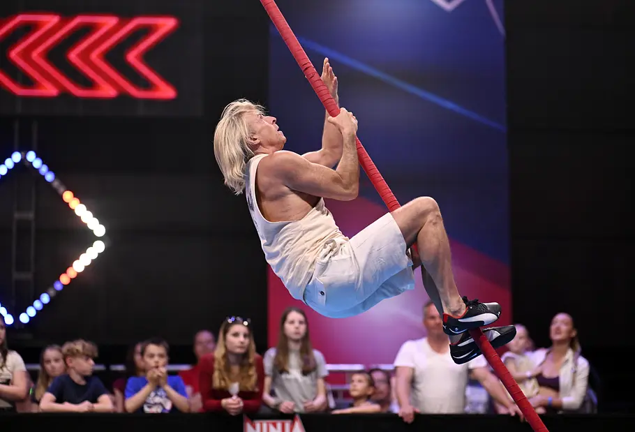 Jens Fodermann ist Teilnehmer bei Ninja Warrior Germany 2026 Jens Fodermann hält sich in weißem Sportoutfit an einer schrägen roten Stange fest. Im Hintergrund steht Publikum.