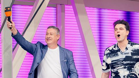 Joachim Llambi und Lutz van der Horst begrüßen das „ZDF Fernsehgarten“-Publikum. Llambi streckt seinen rechten Arm in die Luft, in der Hand hält er ein ZDF-Mikrofon. - Foto: ZDF/Maximilian von Lachner