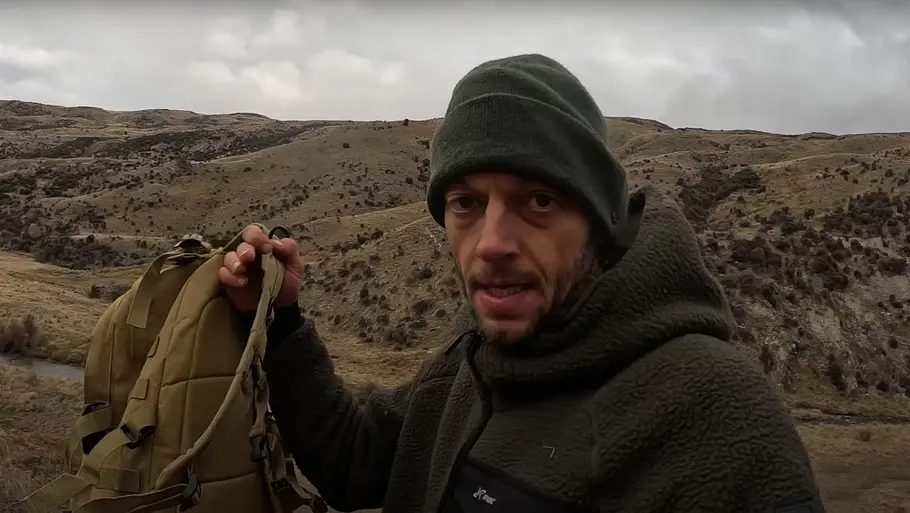 Joe Vogel in Staffel 4 von „7 vs. Wild“. Er hält einen Rucksack hoch.
