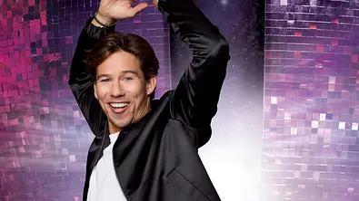 Joel Mattli tanzt vor einer großen Disco-Kugel auf rotem Hintergrund - Foto: RTL / Jörn Strojny