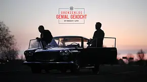 Johann Lafer und Steffen Henssler stehen in der Dämmerung an einem Oldtimer. Darüber steht „Grenzenlos genial gekocht“. - Foto: RTL