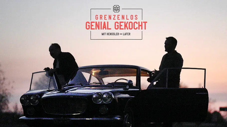 Johann Lafer und Steffen Henssler Johann Lafer und Steffen Henssler stehen in der Dämmerung an einem Oldtimer. Darüber steht „Grenzenlos genial gekocht“.