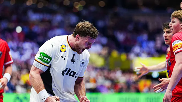 Johannes Golla hat die Fäuste geballt und jubelt ausdrucksstark beim 1. Vorrunden Spiel der EM 2026 gegen Österreich. - Foto: IMAGO / Eibner