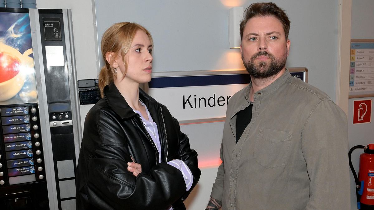 John und Zoe kämpfen ums Sorgerecht. Zoe schaut John mit verschränkten Armen an. Der blickt zur Seite.