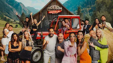  Die Kandidat:innen posieren vor einer rustikalen Scheune mit der Aufschrift „Forsthaus Rampensau Germany“. Im Vordergrund steht ein roter Traktor. Die Personen zeigen verschiedene Posen – einige winken, machen lustige Gesten oder umarmen sich. - Foto: Joyn