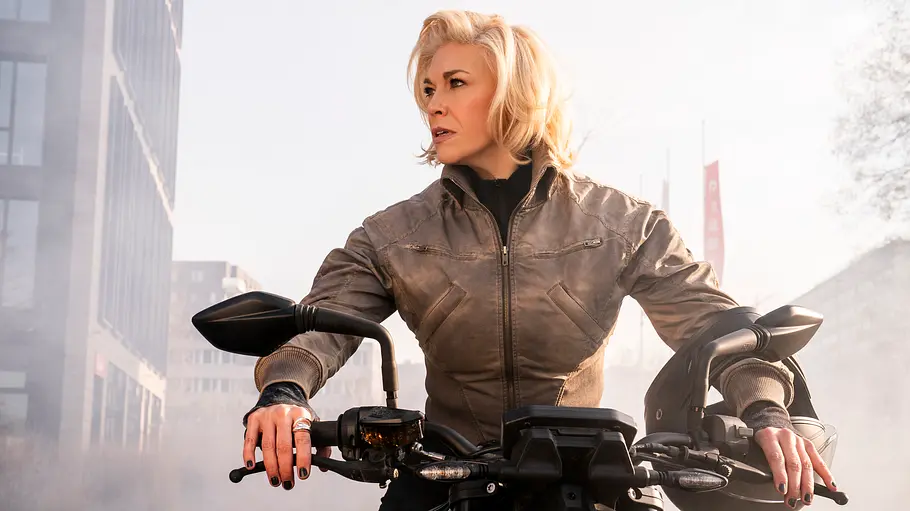 Judith kann das Agentenleben nicht abschütteln. Judith auf einem Motorrad, sie guckt nach rechts.