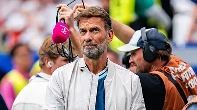 Jürgen Klopp ist für Magenta TV hei der WM 2ß26 im Einsatz. Im Hintergrund sieht man das Übertragungsteam mit einem Mikrofon hantieren. - Foto: IMAGO / Kirchner-Media