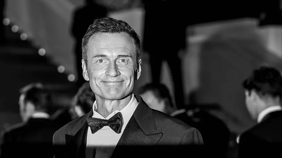 Julian McMahon Julian McMahon trägt einen Anzug mit Fliege und lächelt in die Kamera