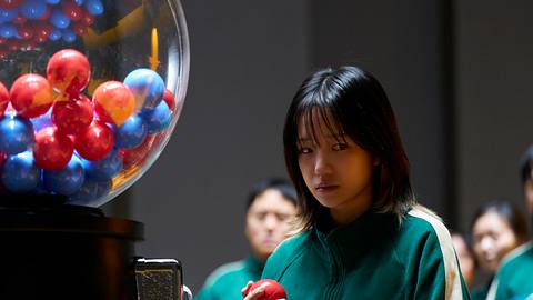 Jun-hee hält einen roten ball in der rechten Hand und schaut nachdenklich zur Seite. - Foto: No Ju-han/Netflix