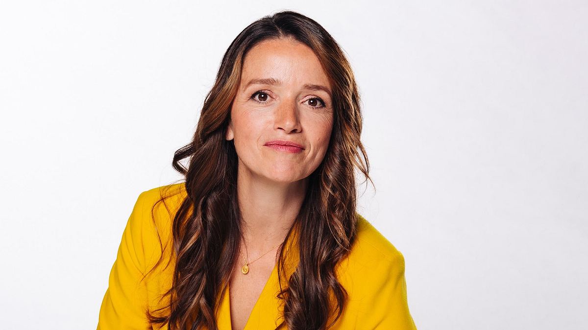 Kaja Schmidt-Tychsen steigt aus! Kaja Schmidt-Tychsen im gelben Anzug mit gewelltem Haar. Sie lächelt direkt in die Kamera.