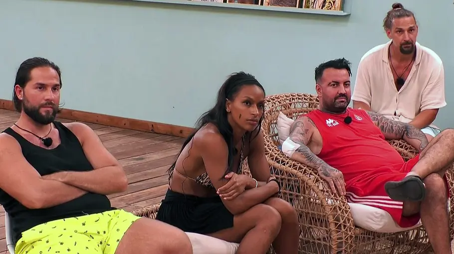 KDRS Vier Personen sitzen in einer gemütlichen Lounge-Umgebung auf Sesseln und Sofa, wirken aufmerksam und etwas angespannt, während sie in die gleiche Richtung schauen; im Hintergrund sind Holzboden und eine schlichte Wand zu sehen.