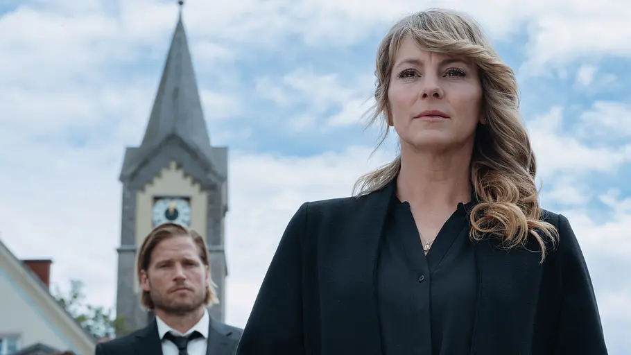 Katharina Bergretter Luise Bähr Katharina steht in schwarzer Kleidung vor einem Blumengesteck. Hinter ihr stehen Markus, Tobi und seine Frau, rechts mit Rosen, und ein Kirchturm.