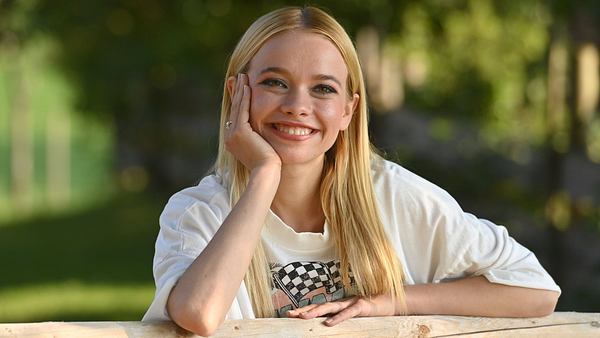 Katharina Hirschberg strahlt mit einem breiten Grinsen in die Kamera. Sie stützt ihre Arme stehend dabei auf einem Holzbalken ab. - Foto: IMAGO / Sven Simon